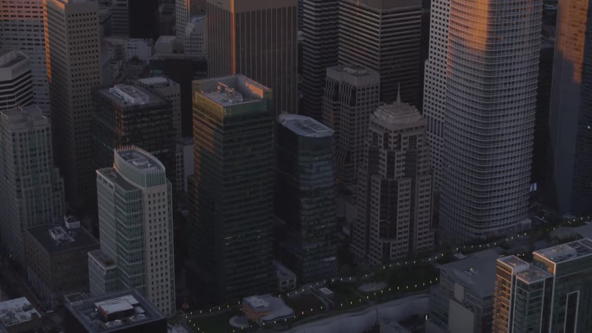 Skyscrapers are illuminated by sunlight in a city at sunset