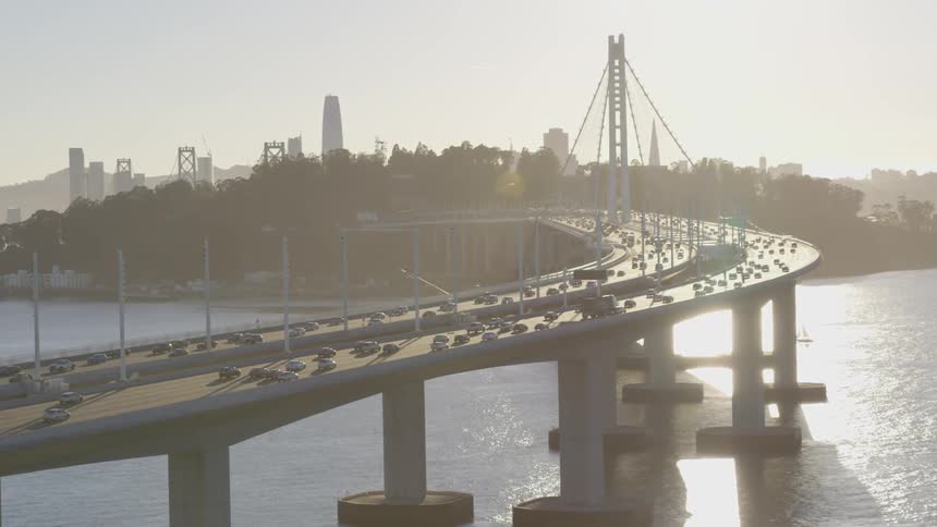 Heavy traffic drives across a long bridge towards a city