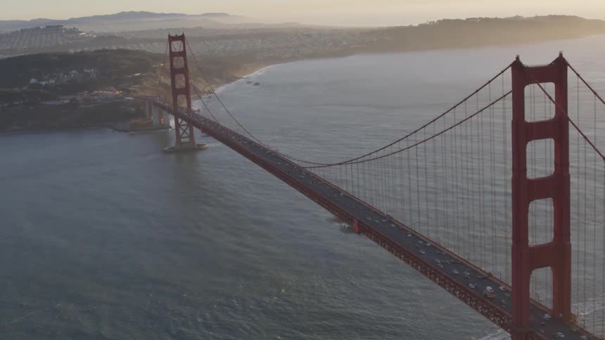 Camera flies over the golden gate bridge at sunset