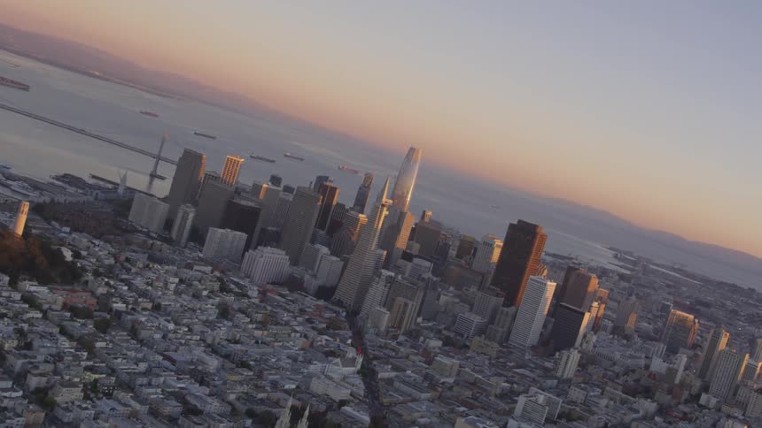A city skyline with the ocean and sunset behind it