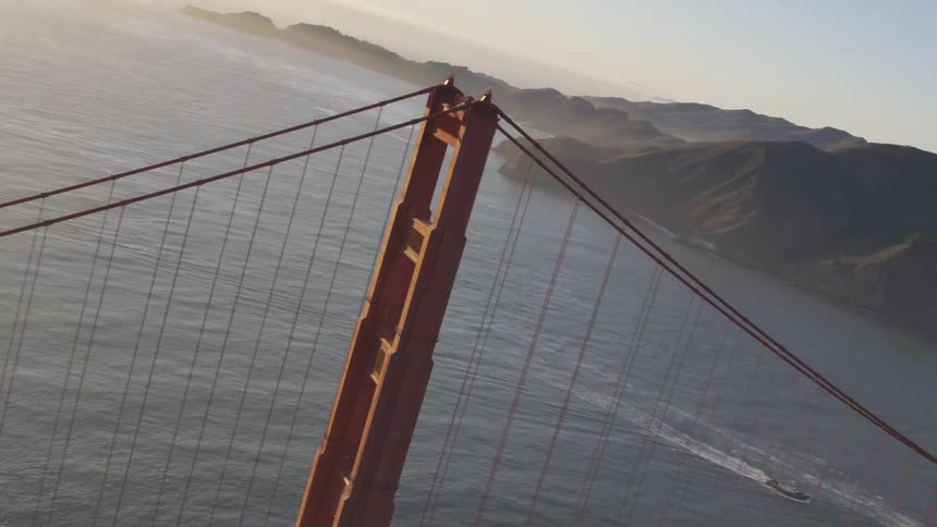 Cars driving on the golden gate bridge suspended over water with boats below