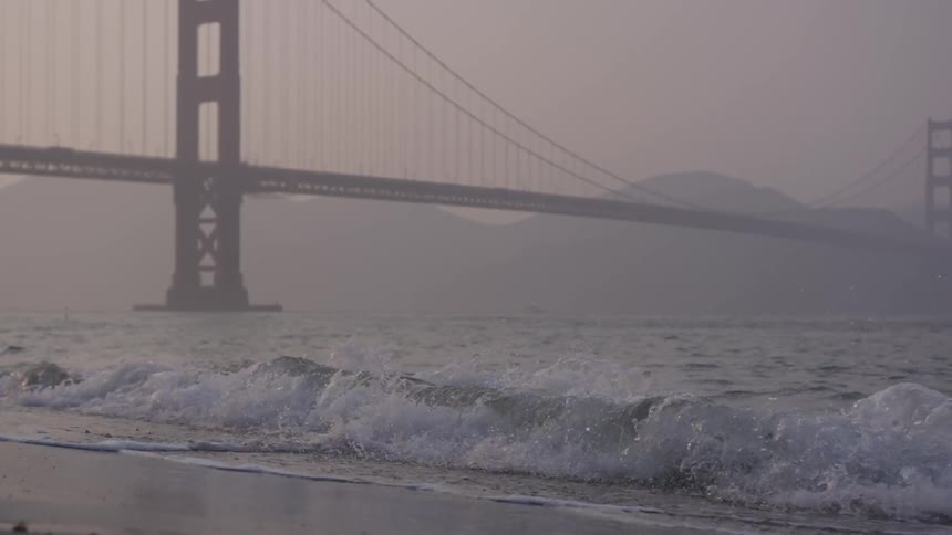 Waves roll to shore beneath the golden gate bridge