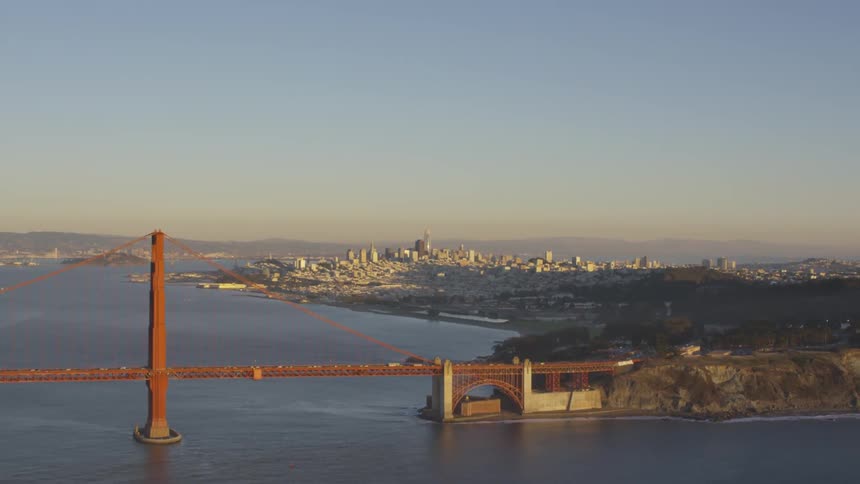 A countryside bridge over a river and city skyline at sunset