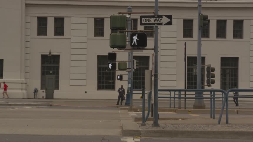 A traffic light changes as people walk by on the other side of the street