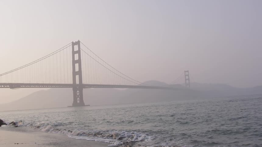 Waves roll to shore beneath the golden gate bridge