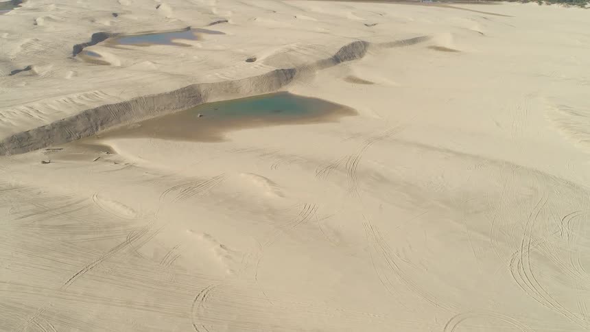 Aerial view of sand with water in the middle of it in the desert