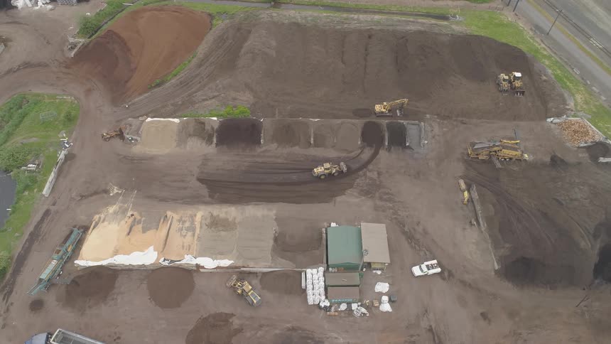 A pickup truck pulls into a sand and gravel pit where a bulldozer is adding to piles