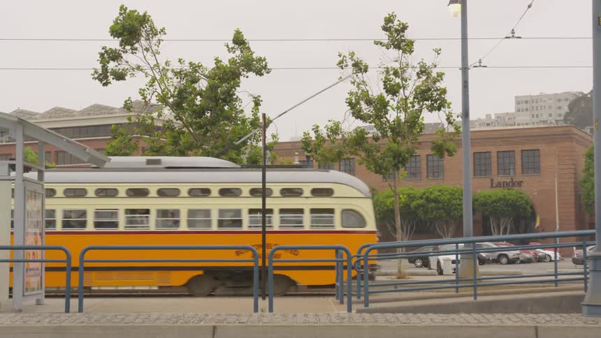 A train goes through a station next to several buildings