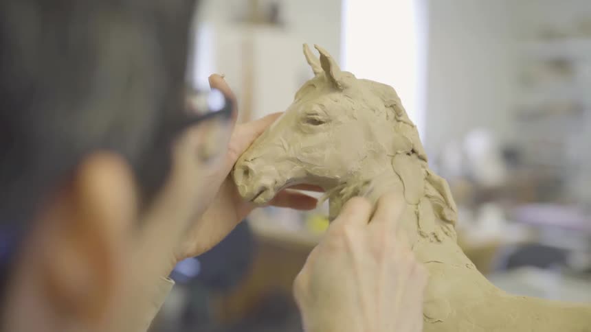 Man sculpts horse out of clay