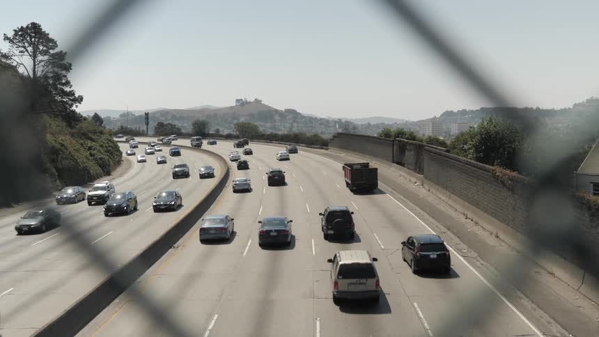 Vehicles drive on highway on a sunny day