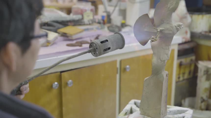 Man uses blowtorch on bird statue