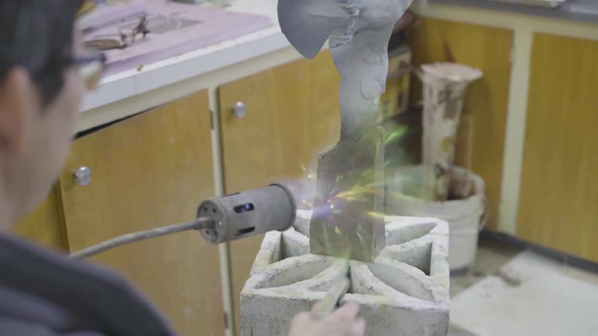 Man using a blowtorch to sculpt metal