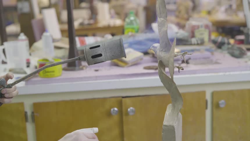 Person torching a sculpture of a bird