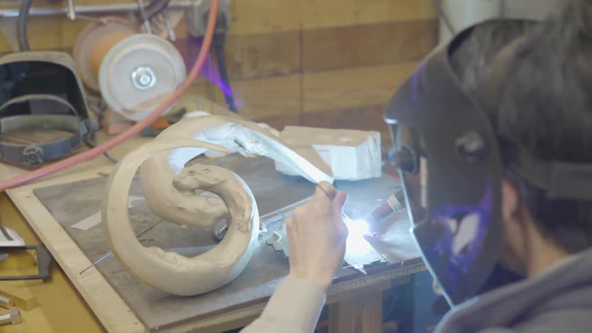 Person uses a welder to weld a wire and a metal plate