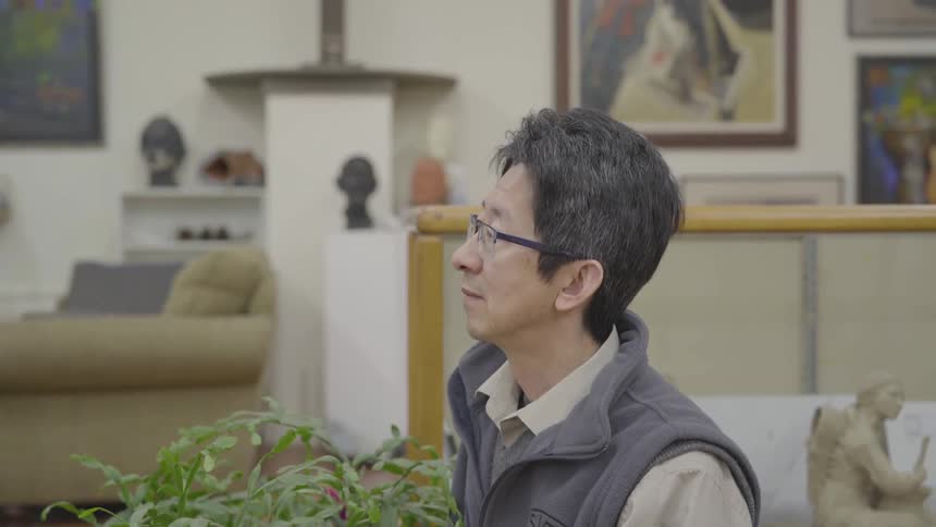A man sitting in a building surrounded by art and sculptures