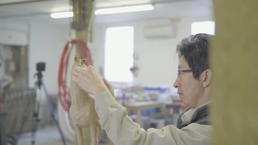 Man shapes a horse sculpture out of clay