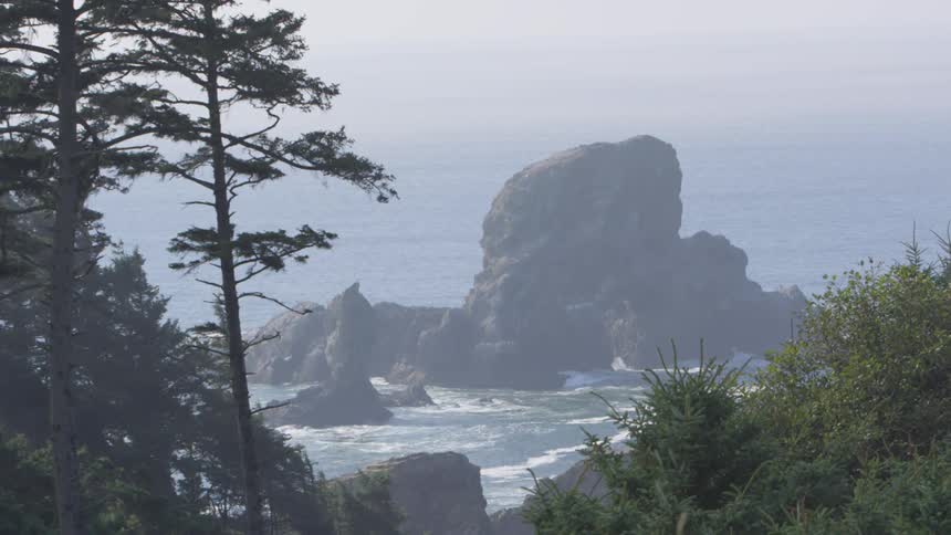 A rock formation off the shore of a land mass