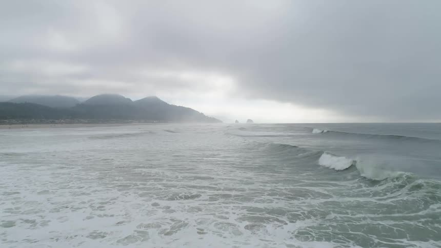 Oceanic waves hit the beach making lots of foam on a cloudy day