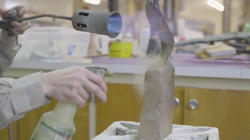 Person welding an art sculpture while spraying it with a liquid