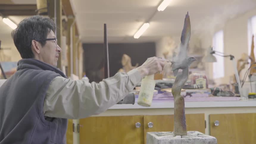 An artist using a torch and spray