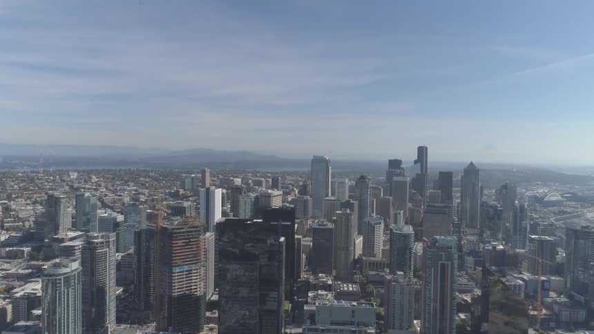 City filled with skyscrapers and buildings sits under a blue sky on a sunny day