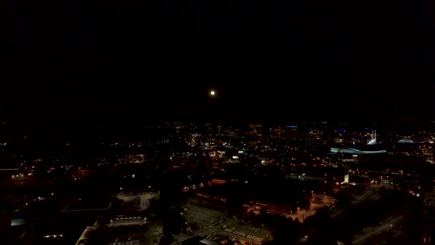 Full moon overlooking the bright lights of the city at night
