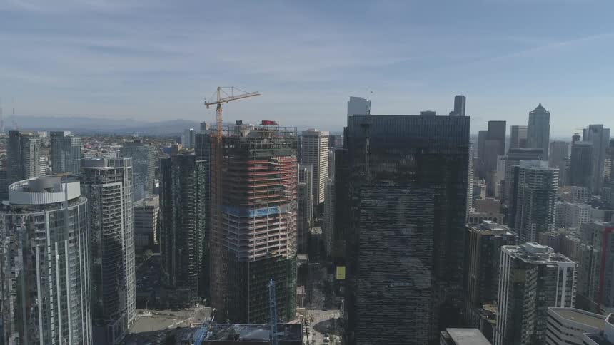 A tall crane stands next to a skyscraper being built in a large city