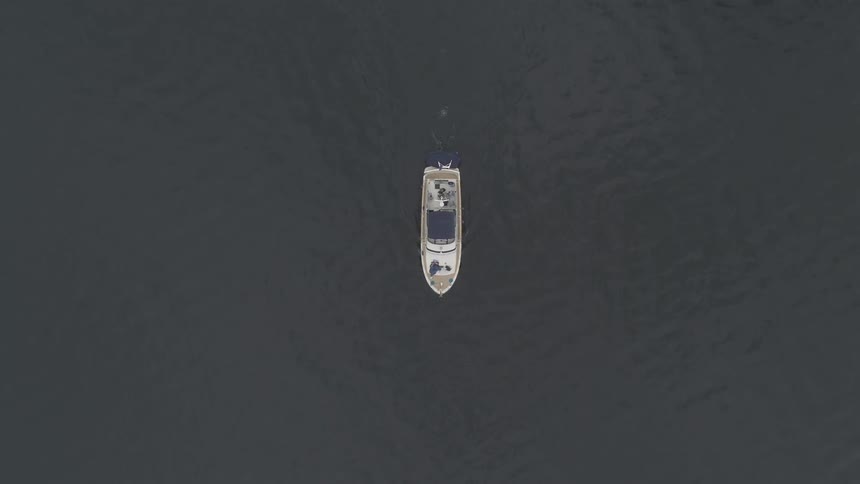 Aerial view of white boat cruising in the middle of the lake