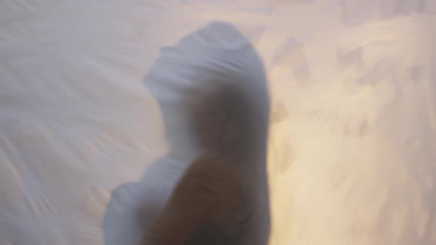Shadow of a person behind a white sheet looking up