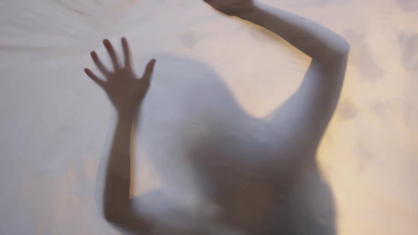 Silhouette of a woman behind a sheet