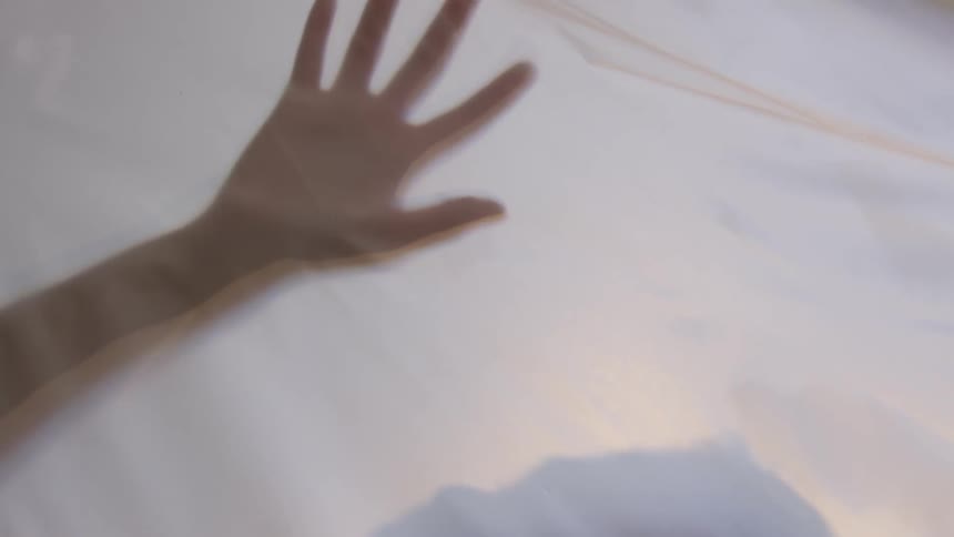 Shadow of person lit up behind white sheet