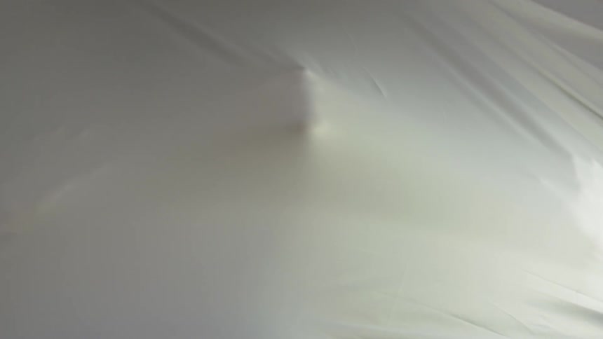 A person puts their face and hands up to a linen sheet