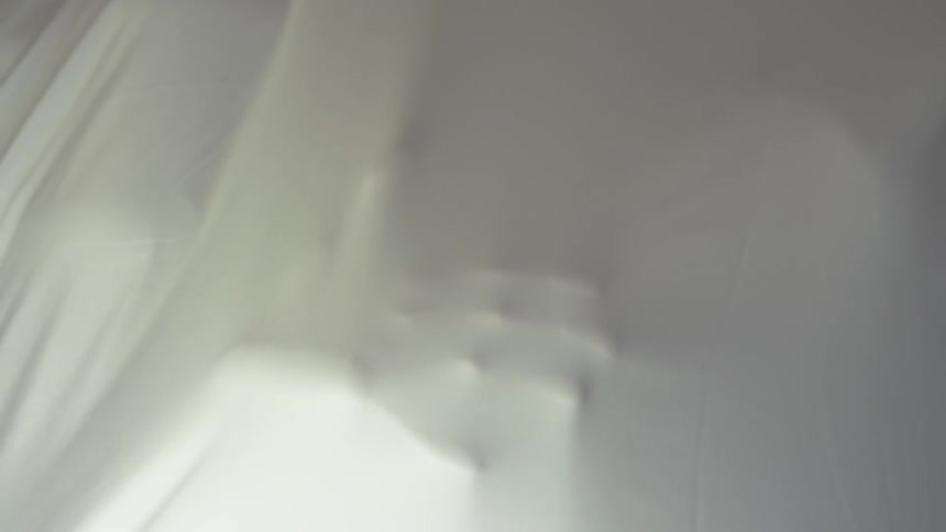 A person's hand presses against white fabric covering them