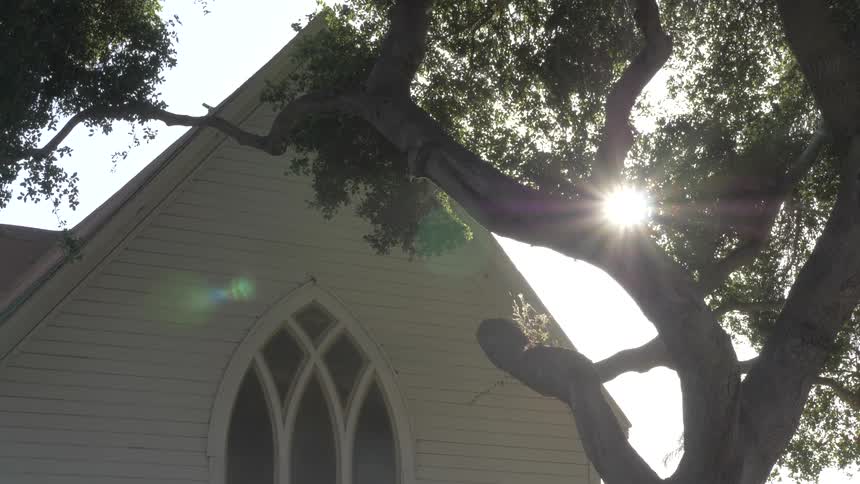 As the camera is pointed upward towards the roof of the house the rays of sunshine are peeking through the trees
