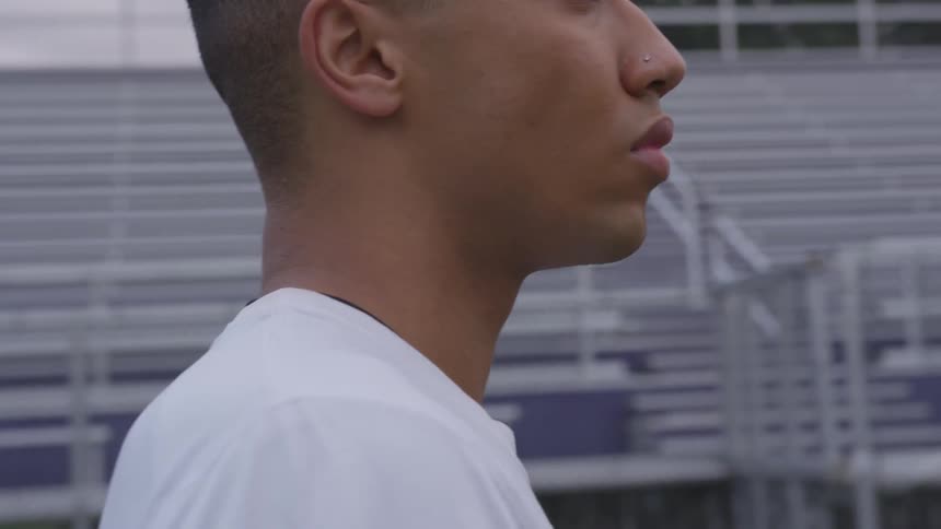 A teenager stands on the field of an empty stadium