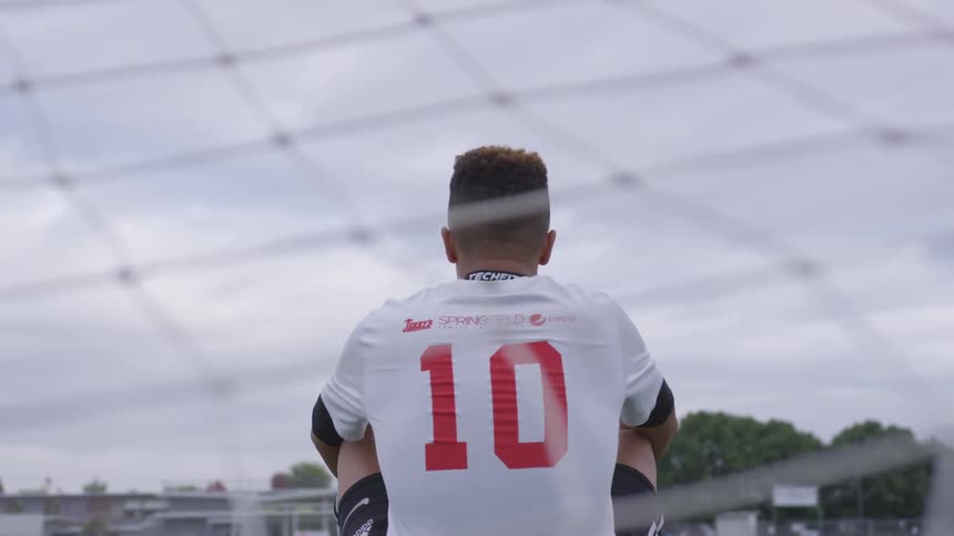 Man in soccer uniform sitting in front of the soccer goal