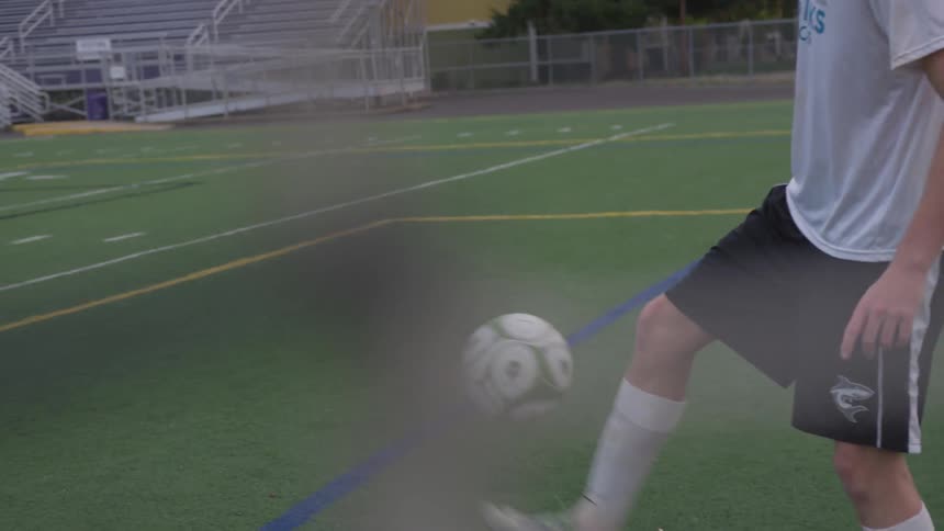 Man dribbles soccer ball on soccer field near goal