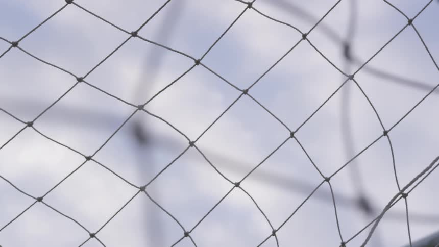A soccer ball flies into a net on an outdoor field