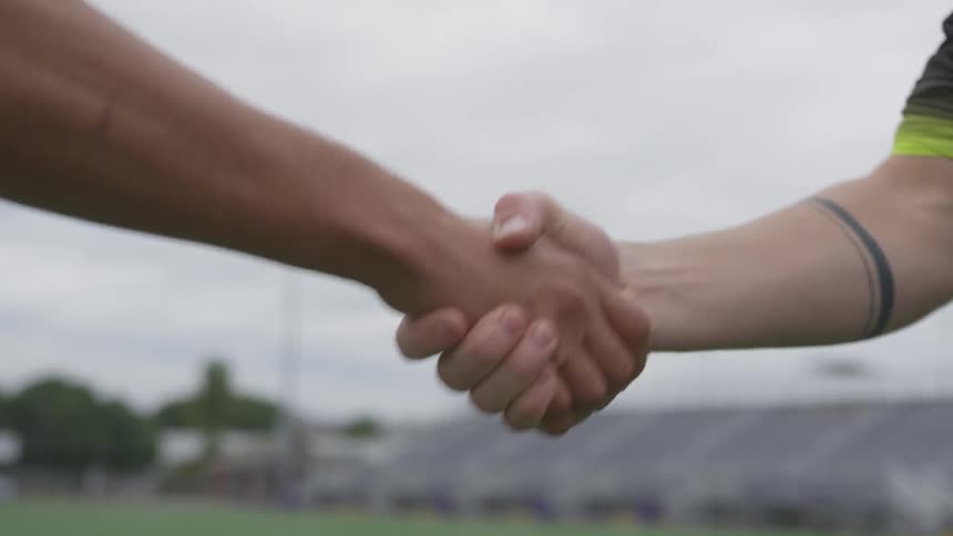 Two people on a field shaking hands