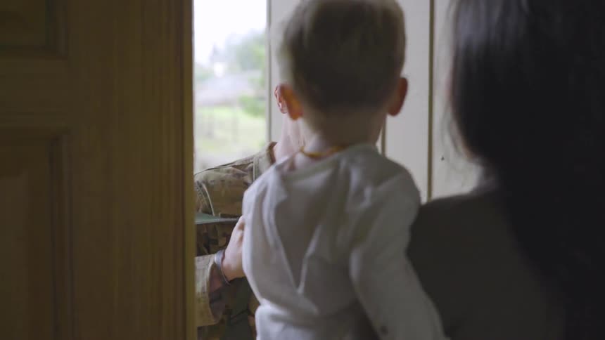 A man in military clothing coming home to a wife and child