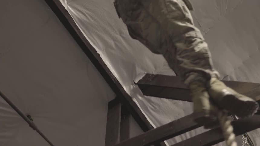 A military man is climbing a rope