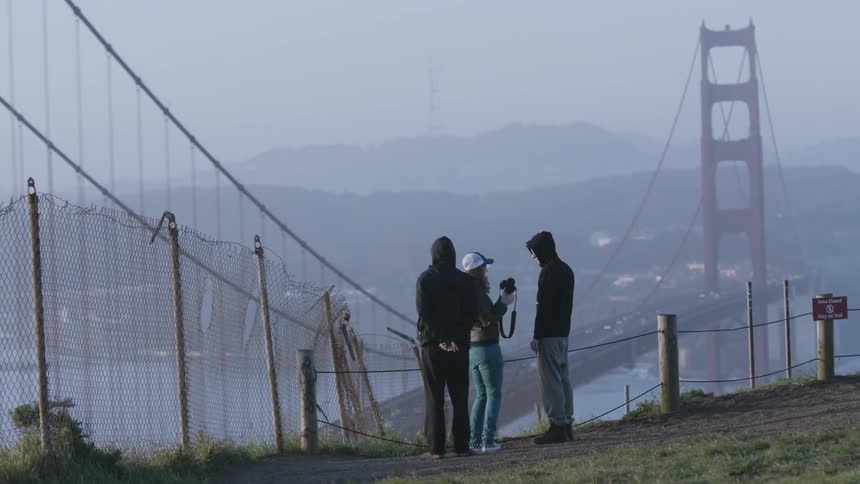 A group of people take a picture in front of a city bridge