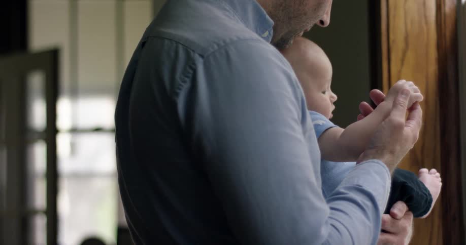 A man holds a baby and kisses it on the head