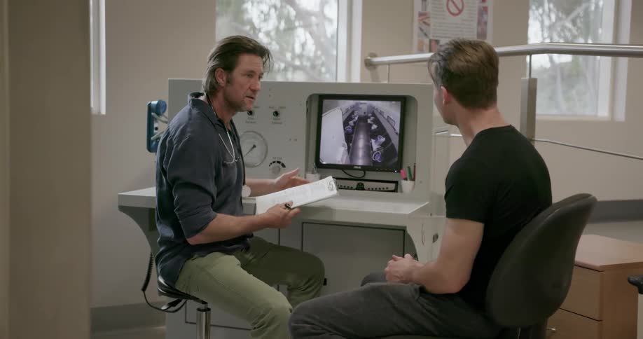 Two men talk while looking at a computer monitor