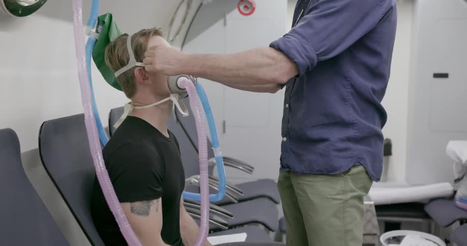 A doctor affixes a breathing mask on a patient in an air cabin