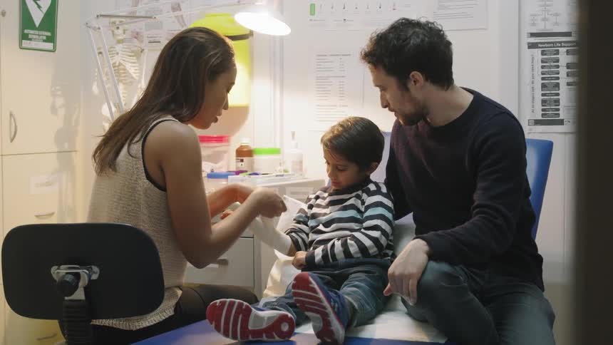 A female doctor attends to a young boy