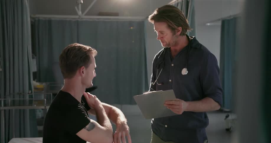 A doctor talks with a patient who is lifting their arm