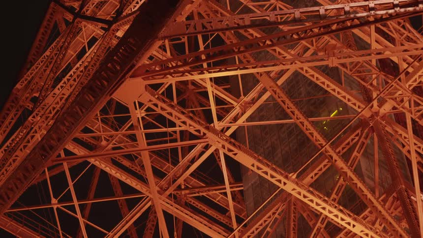 A large metal structure is lit at night with an elevator going down