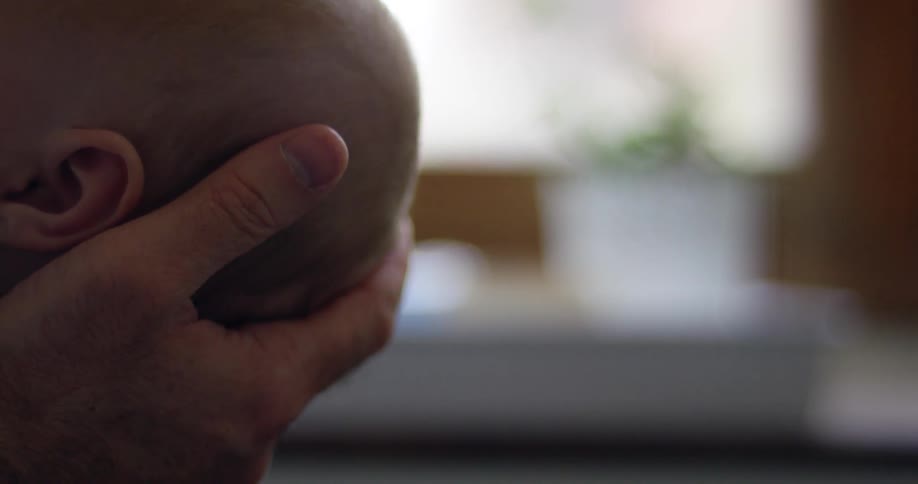 Close up view of a hand holding a baby's head