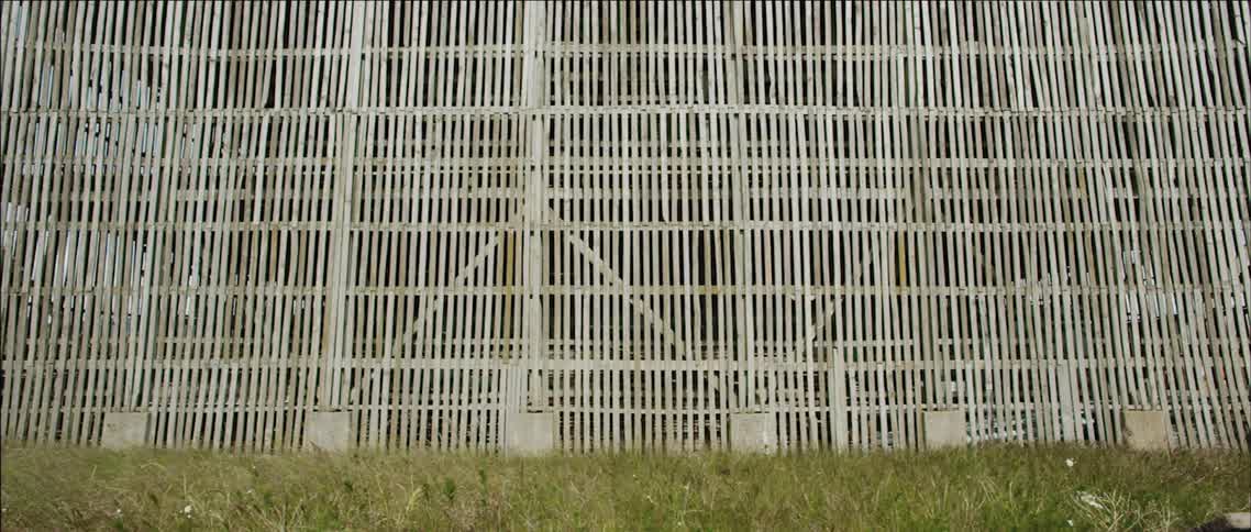 Grass blows in front of a tall structure